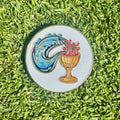 Decorative golf ball marker with a colorful design on grass