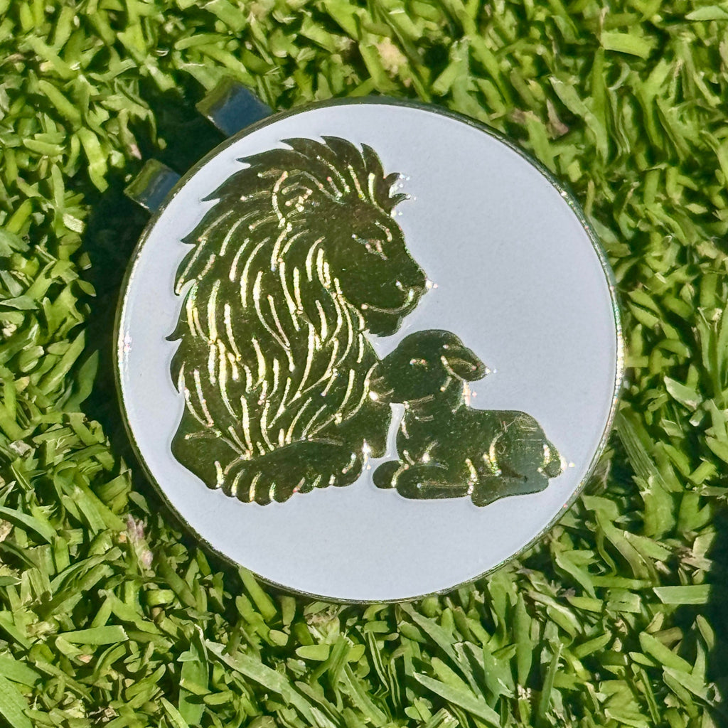 Round metal badge with lion and lamb design on grass